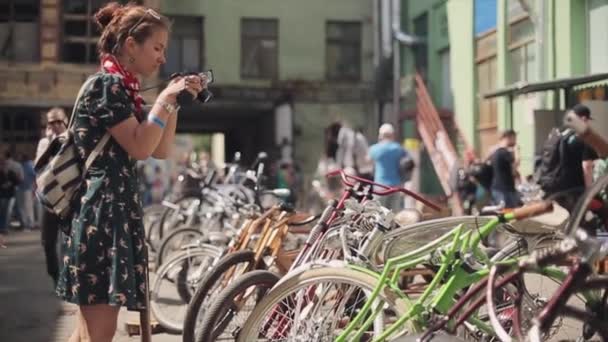 МОСКВА, РОССИЯ - 27 июля 2015 года: Девушка в платье сфотографировала стоящую в очереди на улице велосипедную стойку. Солнечный летний день. Встреча байкеров — стоковое видео