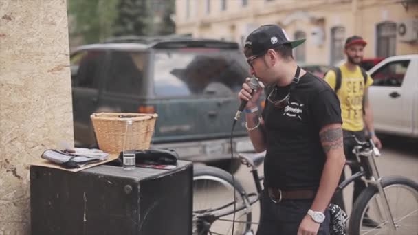 Moskova, Rusya - 27 Temmuz 2015: Gözlüklü, siyah şapkalı gömlekli genç adam mikrofonda konuşuyor. Motorcular toplantısı. Yaz akşamı. — Stok video