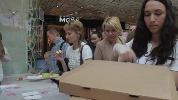 SAN PETERSBURG, RUSIA - 4 DE JUNIO DE 2016: Una niña pone rosquillas de colores en la mesa para la gente del centro comercial. Es justo. Panadería — Vídeos de Stock