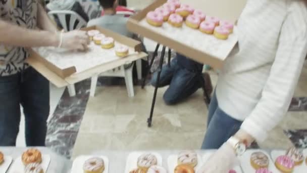 САЙНТ-ПЕТЕРБУРГ, РОССИЯ - 4 ИЮНЯ 2016: Девушка и мальчик положили красочные пончики на стол из коробки в торговом центре. Люди — стоковое видео