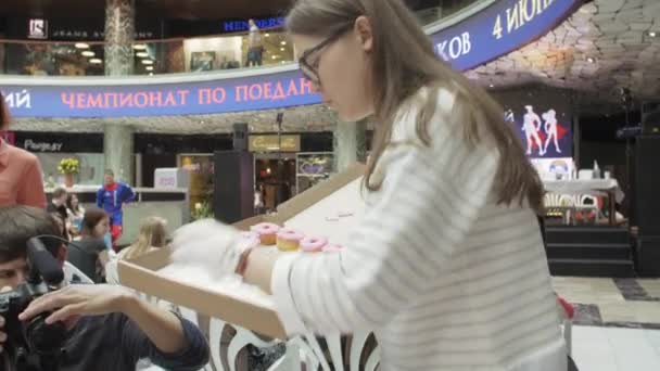 SAINT PETERSBURG, RÚSSIA - JUNHO 4, 2016: Menina colocar donuts coloridos na mesa servida de caixa no centro comercial. Justo . — Vídeo de Stock