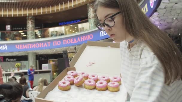 Saint Petersburg, Federacja Rosyjska - 4 czerwca 2016: Dziewczyna umieścić kolorowe pączki na stole serwowane w centrum handlowym. Godziwej. Ludzie. — Wideo stockowe
