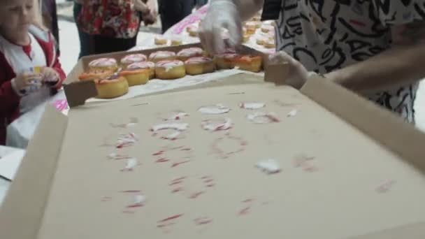 SAINT PETERSBURG, RUSSIA - 4 GIUGNO 2016: L'uomo ha messo una ciambella colorata sul tavolo dalla scatola nel centro commerciale. Bambini. Persone — Video Stock