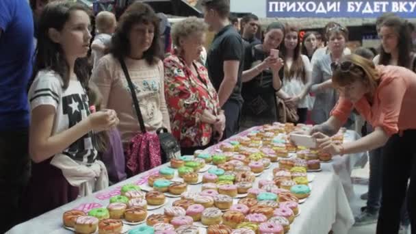 SAINT PETERSBURG, RUSSIE - 4 JUIN 2016 : Table blanche servie avec de nombreux beignets colorés. Boulangerie. Personnes, enfants . — Video