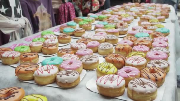 SAINT PETERSBURG, RUSSIE - 4 JUIN 2016 : Table blanche servie avec de nombreux beignets colorés dans un centre commercial. Les gens. Les enfants — Video