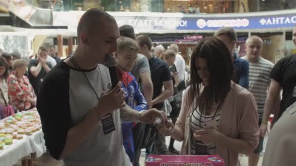 Petrohrad, Rusko - 4 červen 2016: Muž s mikrofon pomoc dívka otevřené loterie míč. Obchodní centrum. Mnoho lidí — Stock video