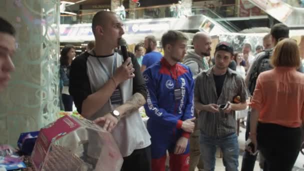 俄罗斯圣彼得堡-2016 年 6 月 4 日 ︰ 男子在彩票框的麦克风。购物中心。在动漫套装来的女孩 — 图库视频影像