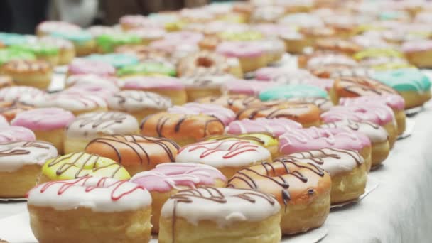 SAN PETERSBURG, RUSIA - 4 DE JUNIO DE 2016: Mesa servida con coloridas rosquillas cubiertas de esmalte. Panadería. Dulces. Gente — Vídeo de stock