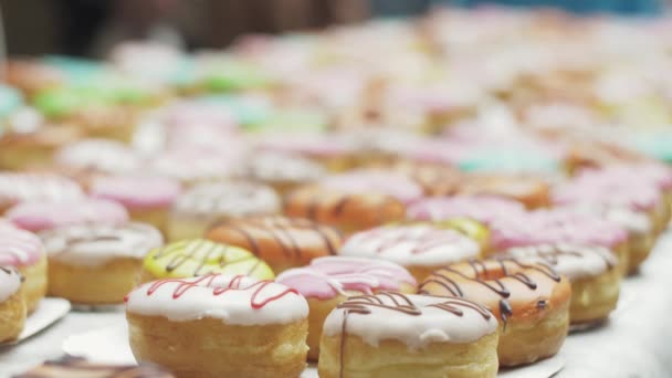 SAN PETERSBURG, RUSIA - 4 DE JUNIO DE 2016: Mesa llena de coloridas rosquillas cubiertas de esmalte. Panadería. Dulces. Gente . — Vídeo de stock