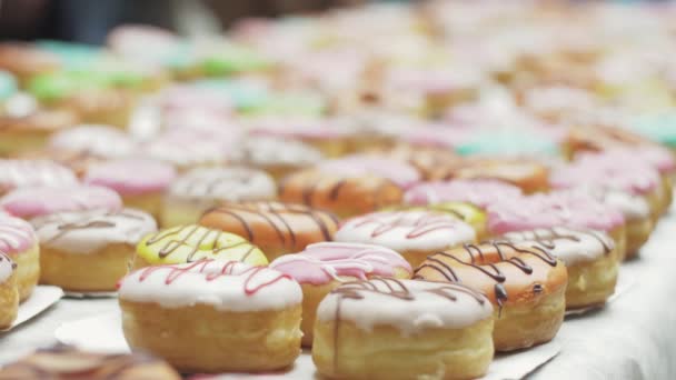 СЕНТ-ПЕТЕРБУРГ, РОССИЯ - 4 ИЮНЯ 2016: Стол подается со многими красочными пончиками, покрытыми глазурью. Пекарня. Люди — стоковое видео