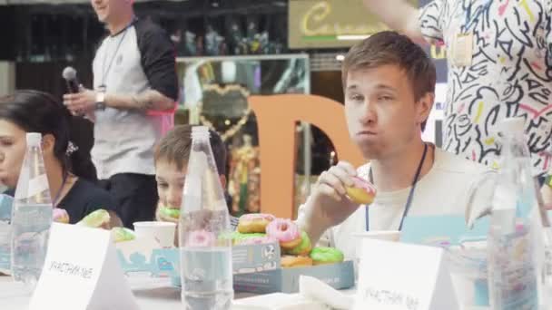 Sankt Petersburg, Rosja-4 czerwca 2016: ludzie jedzą pączki w białym stole na prędkości. Konkurs. Rozrywka. — Wideo stockowe