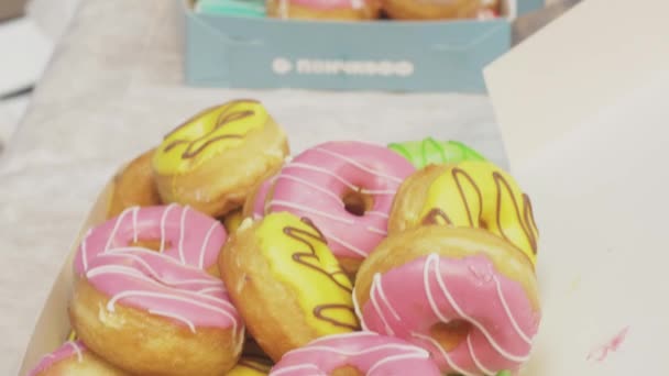 SAINT PETERSBURG, RUSSIE - 4 JUIN 2016 : Boîtes avec de nombreux beignets colorés recouverts de glaçure sur la table. Boulangerie. Les gens — Video