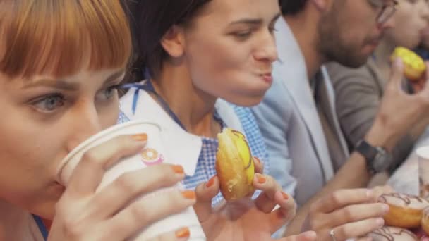 圣彼得堡，俄罗斯-2016 年 6 月 4 日 ︰ 人吃美味甜甜圈涵盖的釉在桌上的速度。比赛 — 图库视频影像