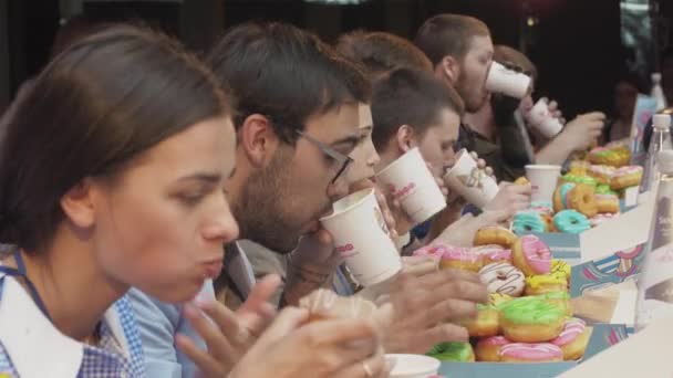 SAN PETERSBURG, RUSIA - 4 DE JUNIO DE 2016: La gente come rosquillas cubiertas de glaseado a la velocidad de la mesa. Concurso. Ríete. — Vídeos de Stock