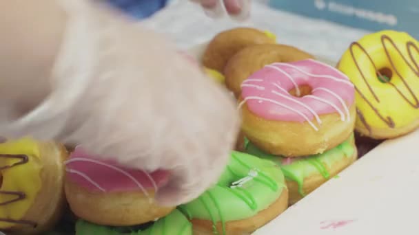 SAN PETERSBURG, RUSIA - 4 DE JUNIO DE 2016: La niña con guantes cuenta coloridas rosquillas cubiertas de esmalte en caja. Panadería. Dulces. — Vídeo de stock