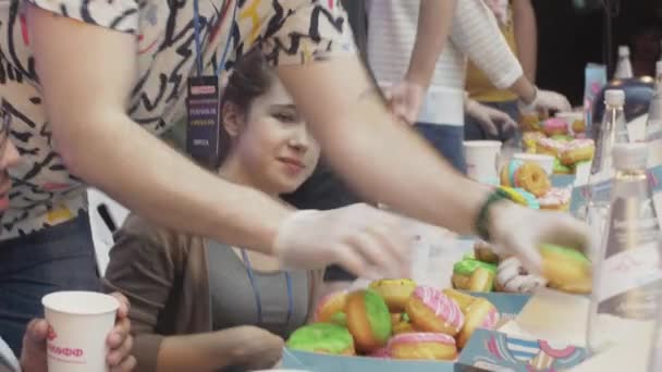 SAN PETERSBURG, RUSIA - 4 DE JUNIO DE 2016: El hombre cuenta con rosquillas coloridas cubiertas de esmalte en caja. Concurso. Gente. Evento — Vídeos de Stock