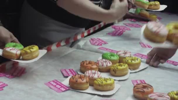 Sint-Petersburg, Rusland - 4 juni 2016: Mensen nemen kleurrijke donuts uit tabel. Shopping center. Dessert. Evenement — Stockvideo