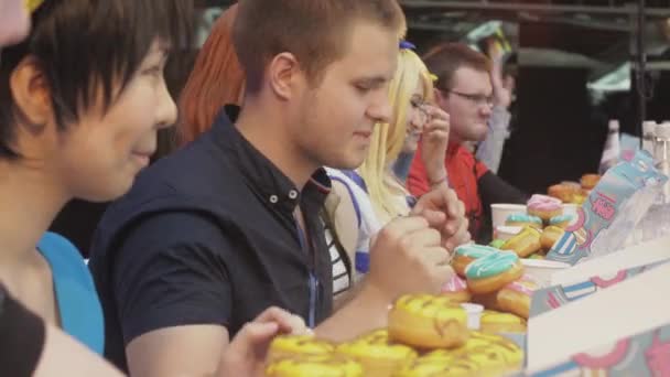 SAINT PETERSBURG, RÚSSIA - JUNHO 4, 2016: Pessoas sentadas à mesa com caixas com muitos donuts apetitosos. Concurso — Vídeo de Stock