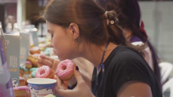サンクトペテルブルク, ロシア連邦 - 2016 年 6 月 4 日: 女の子は速度のテーブルに釉薬で覆われてドーナツを食べる。コンテスト。選手権 — ストック動画