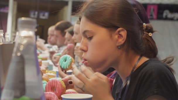 Санкт-Петербург, Російська Федерація - 4 червня 2016: Хлопчики і дівчатка їдять пончики покриті глазурі столом на швидкість. Чемпіонат — стокове відео