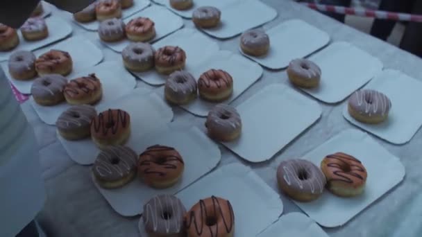 SAINT PETERSBURG, RÚSSIA - JUNHO 4, 2016: Menina de luvas colocar donuts coloridos na mesa no centro comercial. É justo. Pessoas . — Vídeo de Stock