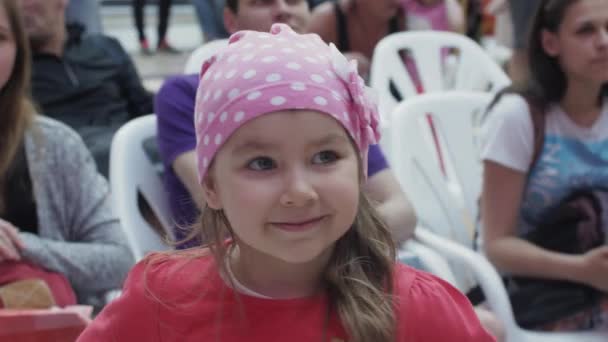 SAINT PETERSBURG, RÚSSIA - JUNHO 4, 2016: A menina sorri na câmera. As pessoas sentam-se em cadeiras no centro comercial. Evento — Vídeo de Stock