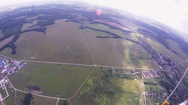 Скайдайвер летает на парашюте в воздухе. Зеленые поля. Полет. Летний день. Высота — стоковое видео