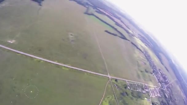 Скідайвер летить на парашуті над зеленим полем. Політ. Літній день. Екстремальні види спорту — стокове відео