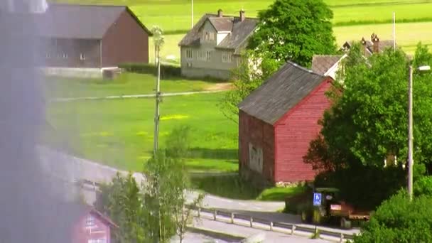 Wasserfall plätschert vor der Kamera. Holzhäuschen. Sommer. grünes Gras. Agrarmotor geht auf die Straße — Stockvideo