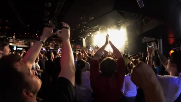 Petrohrad, Rusko-26. června 2015: davy lidí zvedají ruce, tleskají v nočním klubu na diskotéku. Reflektor. Fandění. Koncertní koncert — Stock video
