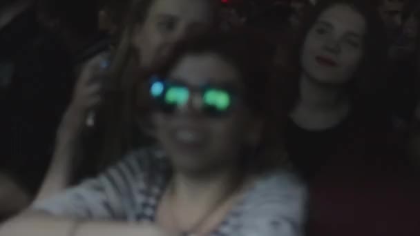 СЕНТ-ПЕТЕРБУРГ, РОССИЯ - 26 ИЮНЯ 2015: Девушка в солнечных очках, мужчина неуклюже танцует на дискотеке в ночном клубе среди толпы. Прожекторы . — стоковое видео