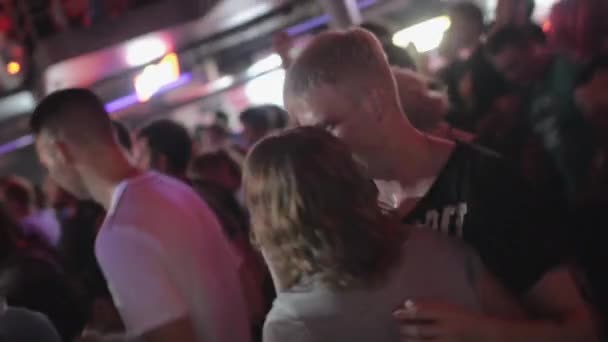 Sint-Petersburg, Rusland - 26 juni 2015: Paar tieners dansen op discotheek in nachtclub onder menigte. Schijnwerpers. Verhoogde balalaika. — Stockvideo