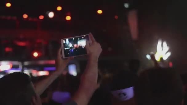 Sint-Petersburg, Rusland - 26 juni 2015: Man schieten op Tablet PC prestaties van folk rockband op discotheek in nachtclub. Schijnwerpers. — Stockvideo