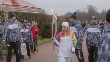 Saint Petersburg, Rusya - 27 Ekim 2013: bayrak yarışı Olimpiyat alev Peterhof, Saint Petersburg içinde. Işık tutan kimse dalga el, pass alev. Gönüllü