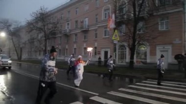 Saint Petersburg, Rusya - 27 Ekim 2013: St. Petersburg'da bayrak yarışı Olimpiyat ateşi. Meşale taşıyıcısı yağmur altında alev ile çalıştırın. Akşam. Muhafız