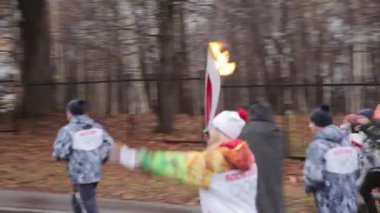 Saint Petersburg, Rusya - 27 Ekim 2013: St. Petersburg'da bayrak yarışı Olimpiyat ateşi. Kadın meşale taşıyıcısı yolda alev le koşar. Muhafız