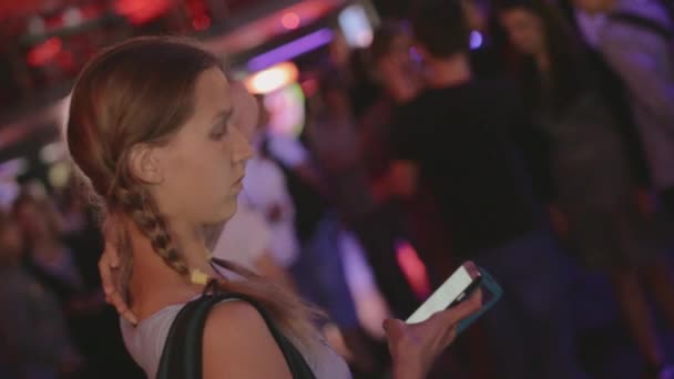 SAN PETERSBURG, RUSIA - 26 DE JUNIO DE 2015: Niña con coletas al teléfono en la discoteca. Mucha gente. Adolescentes. Dispositivo. Fiesta nocturna — Vídeos de Stock