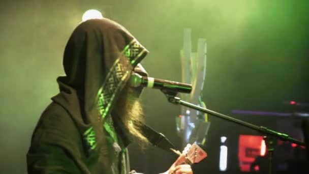 SAINT PETERSBURG, RUSIA - 26 DE JUNIO DE 2015: Vocalista barbudo en el manto interpreta a balalaika en el escenario de la discoteca. Proyectores verdes. Actuación en vivo — Vídeos de Stock