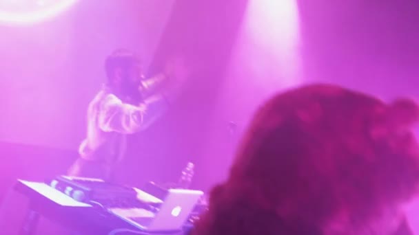SAINT PETERSBURG, RUSIA - 26 DE JUNIO DE 2015: Vocalista barbudo en el manto interpreta a balalaika en el escenario de la discoteca. DJ, hombre como oso. Proyectores rosados . — Vídeos de Stock