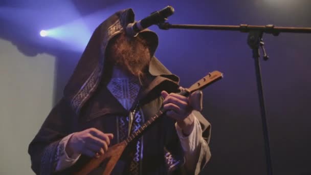 SAINT PETERSBURG, RÚSSIA - JUNHO 26, 2015: Vocalista de manto, homem de roupas folclóricas com machado no palco em boate. Holofotes azuis. Banda musical — Vídeo de Stock