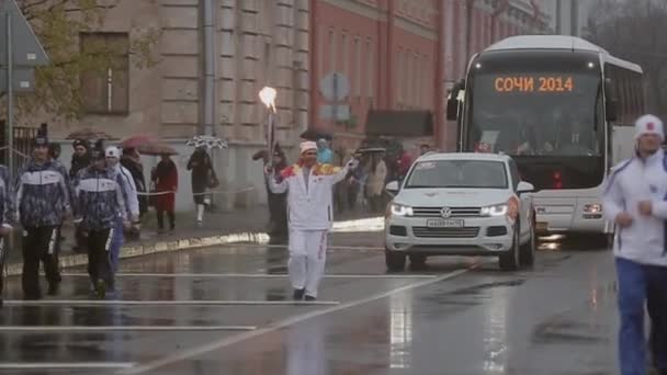 SAN PETERSBURG, RUSIA - 27 DE OCTUBRE DE 2013: Carrera de relevos Llama olímpica en San Petersburgo en octubre. Bari Alibasov correr con llama, la mano de la onda . — Vídeo de stock