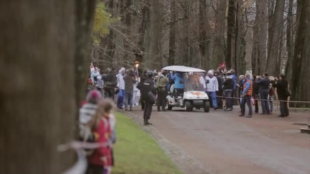 SAN PETERSBURG, RUSIA - 27 DE OCTUBRE DE 2013: Carrera de relevos Llama olímpica en Peterhof, San Petersburgo. Cortejo con el portador de la antorcha, vagón en el parque — Vídeo de stock