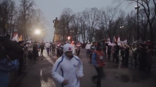 SAINT PETERSBURG, RUSSIA - OCTOBER 27, 2013: Relay race Olympic flame in Saint Petersburg. Torchbearer run with flame. Guards. Evening. Monument — Stock Video