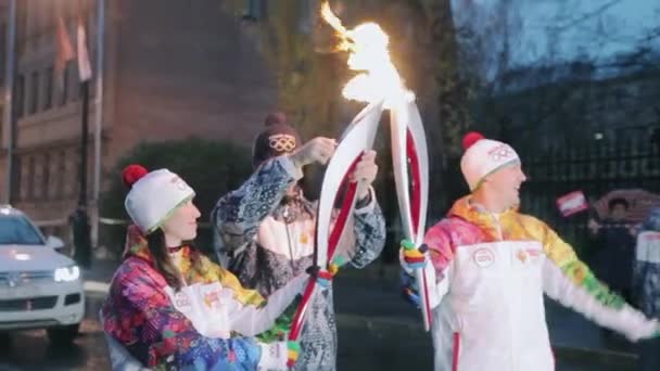 俄罗斯圣彼得堡 - 2013年10月27日：接力赛奥运圣火在圣彼得堡举行。火炬手将圣火传递给女性。晚上。挥动手 — 图库视频影像