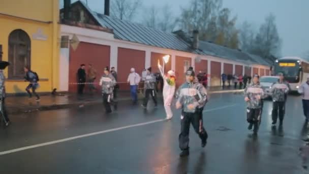SAINT PETERSBURG, RUSSIA - OCTOBER 27, 2013: Relay race Olympic flame in Saint Petersburg. Torchbearer run with flame on street, wave hand. Guard — Stock Video
