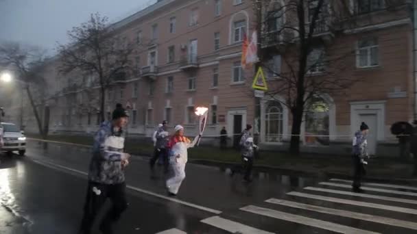 SAINT PETERSBURG, RUSSIA - OCTOBER 27, 2013: Relay race Olympic flame in Saint Petersburg. Torchbearer run with flame under rain. Evening. Guards — Stock Video