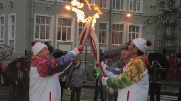 SAINT PETERSBURG, RUSSIA - OCTOBER 27, 2013: Relay race Olympic flame in Saint Petersburg. Bari Alibasov pass flame to torchbearer. Evening. Rain — Stock Video