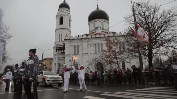 Αγία Πετρούπολη, Ρωσία-27 Οκτωβρίου 2013: ιπποδρομία της Ολυμπιακής φλόγας στην Αγία Πετρούπολη. Ο λαμπαδοκομιστής περνάει φλόγα στη γυναίκα. Το χέρι του κύματος. Καθεδρικός ναός — Αρχείο Βίντεο
