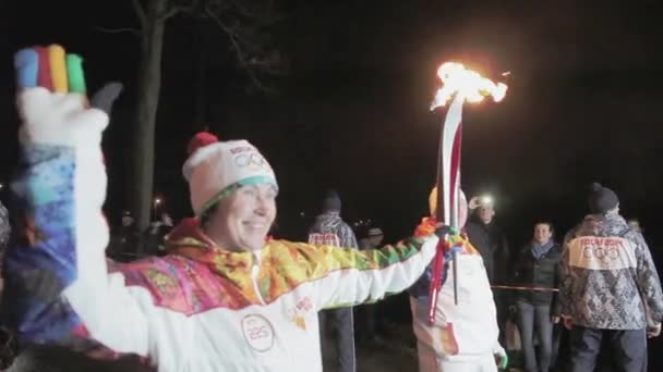 Sankt Petersburg, Ryssland-oktober 27, 2013: relä Race olympisk flamma i Sankt Petersburg. Torchbärare passera flamma Lyubov Yegorova. Mörka kvällen — Stockvideo