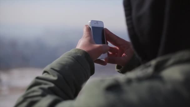 Achterkant van man schieten op telefoon panorama van de stad bekijken platform. Zonnige dag. Koude tinten. — Stockvideo